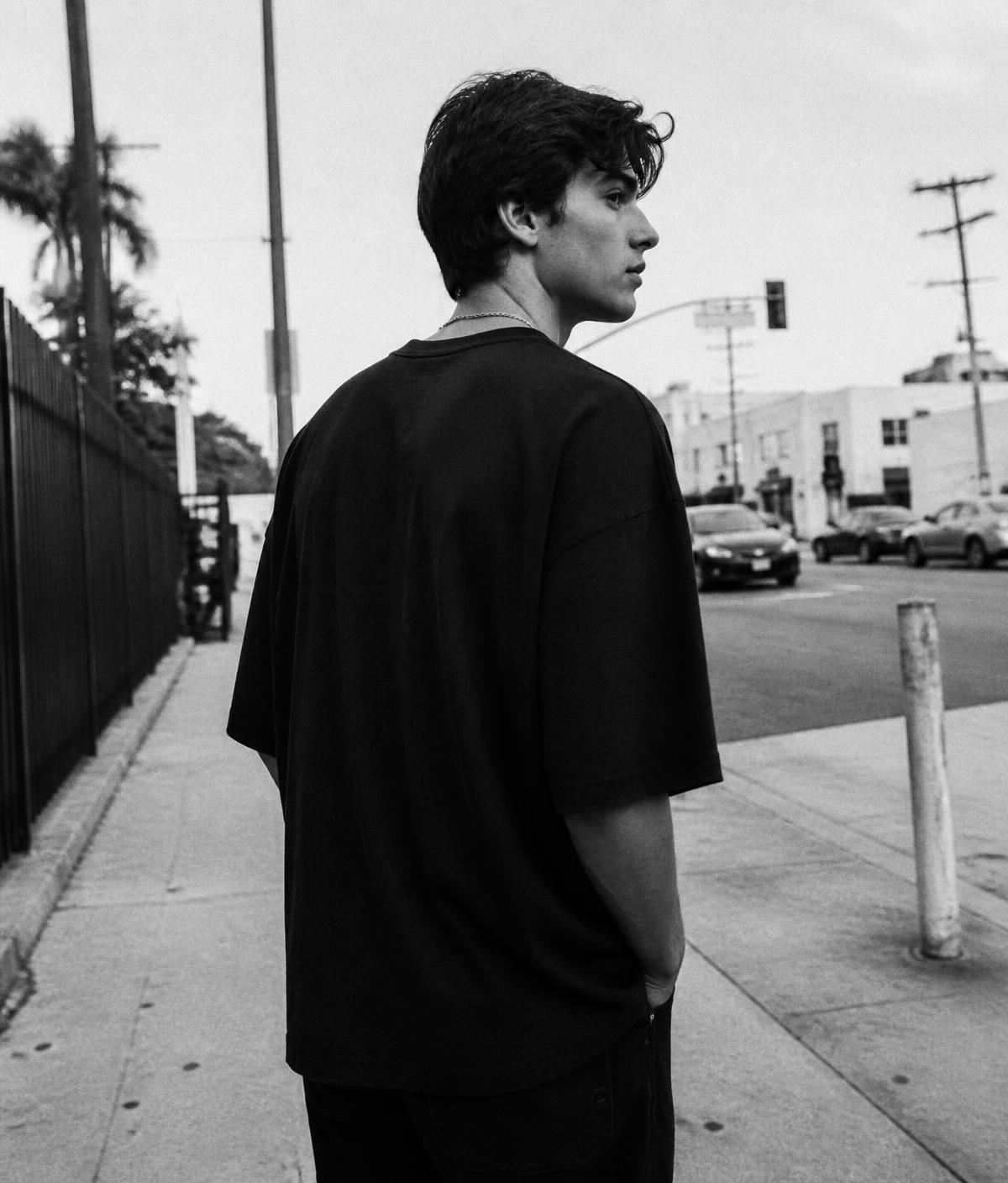 Someone wearing a black oversized MORO shirt on a Los Angeles street
